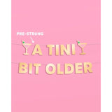 A Tini Bit Older Gold Foil Banner - 5 Ft. | Martini Decoration, Birthday Party Sign, Casino Decor, Girl Cocktail Backdrop, Vegas Photo Booth Background