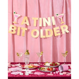 A Tini Bit Older Gold Foil Banner - 5 Ft. | Martini Decoration, Birthday Party Sign, Casino Decor, Girl Cocktail Backdrop, Vegas Photo Booth Background